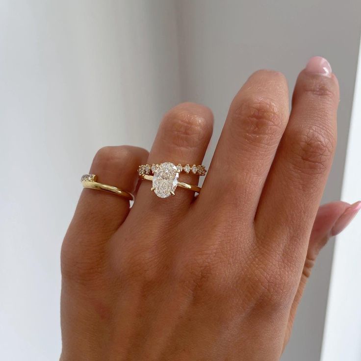 a woman's hand with two different rings on her left and the middle finger