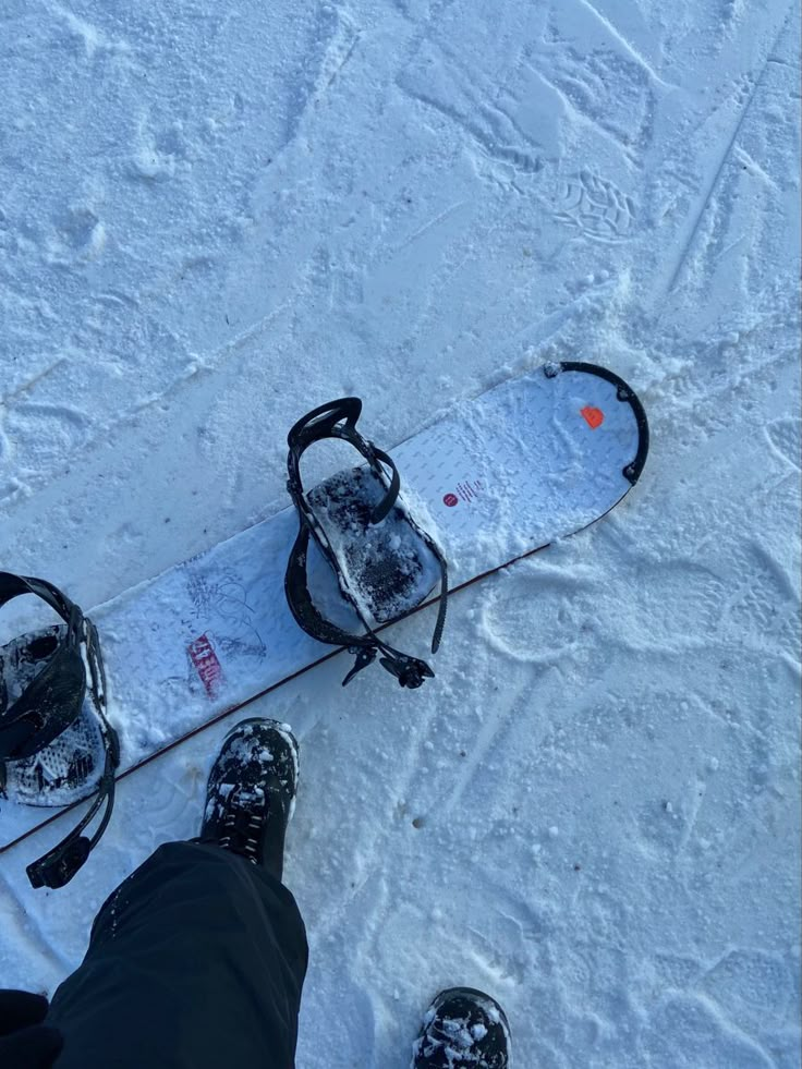 the snowboarder is standing in the snow with his feet on the snow covered ground