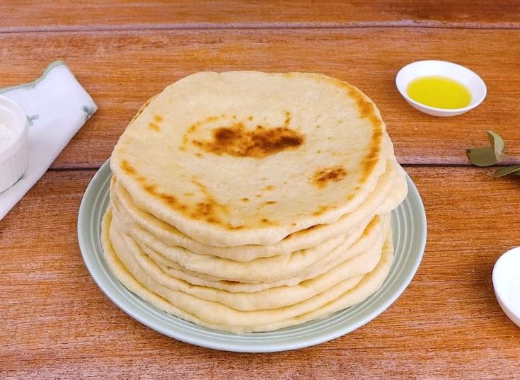 a stack of flat bread sitting on top of a plate next to some sauces