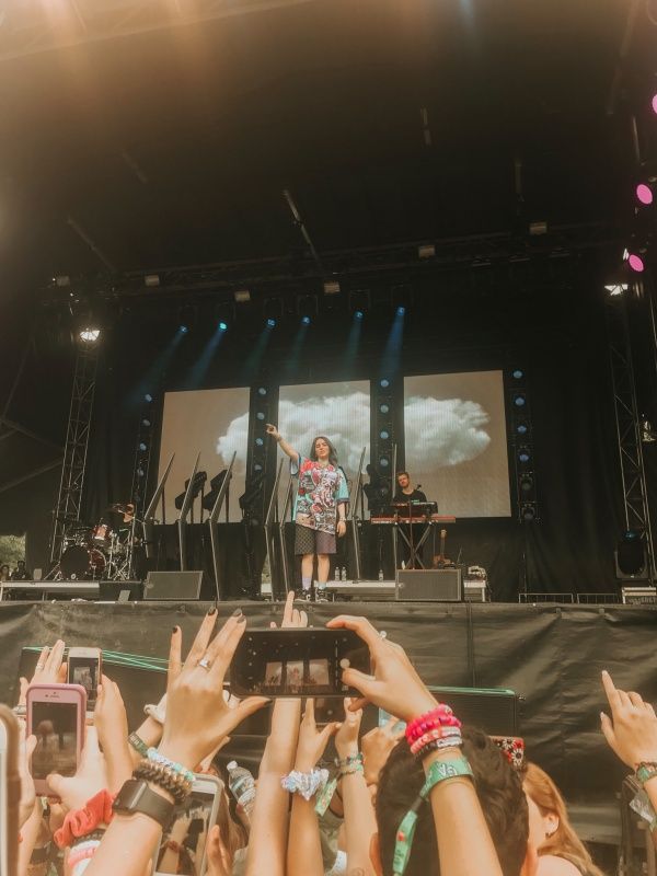 a woman standing on top of a stage holding a cell phone in front of her