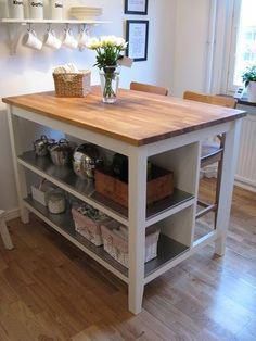 a kitchen island with two shelves on each side and flowers in the center, sitting next to an open window