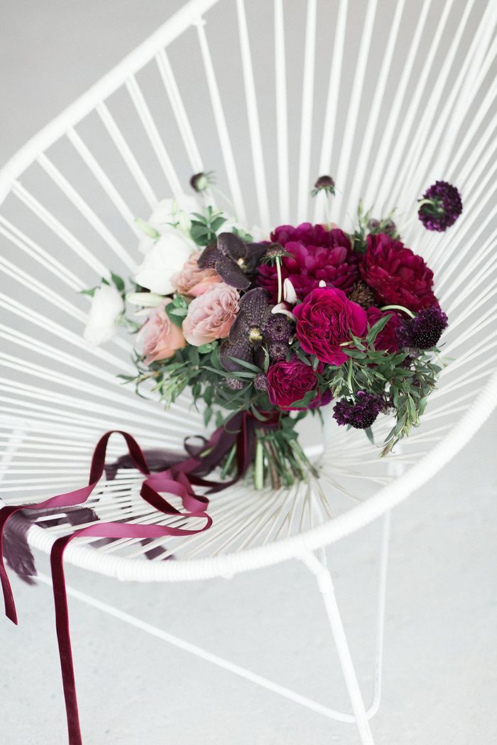 a bouquet of flowers sitting on top of a white chair next to a red ribbon