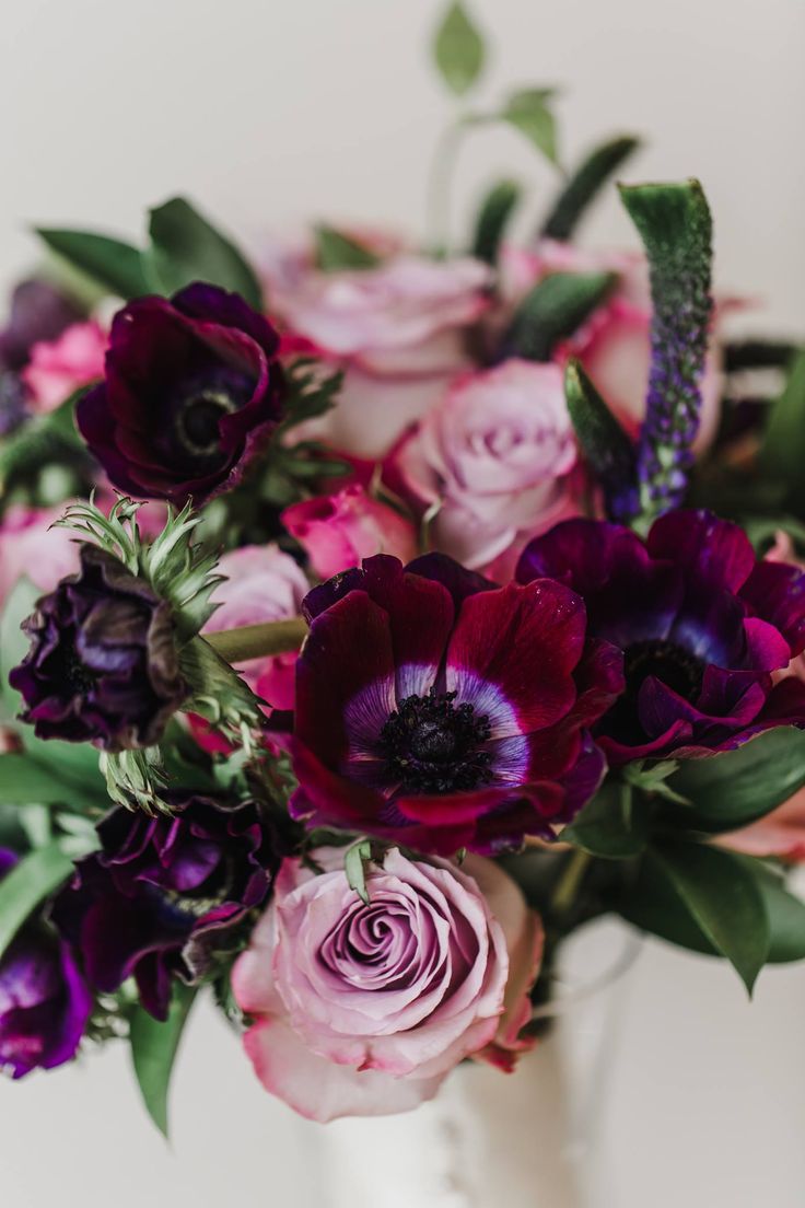 a white vase filled with purple and pink flowers