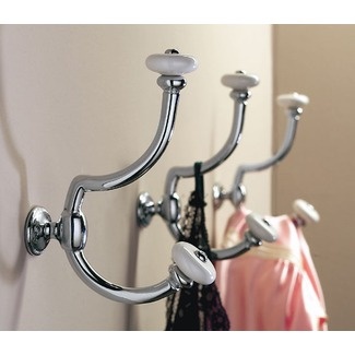 a coat rack with two coats hanging from it's hooks and a pink shirt on the hanger