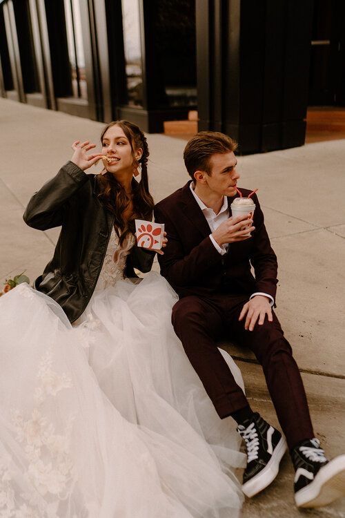 a man and woman are sitting on the ground drinking coffee together, while one is wearing a tuxedo