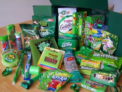 an assortment of snacks and candy sitting on a wooden table next to a green box