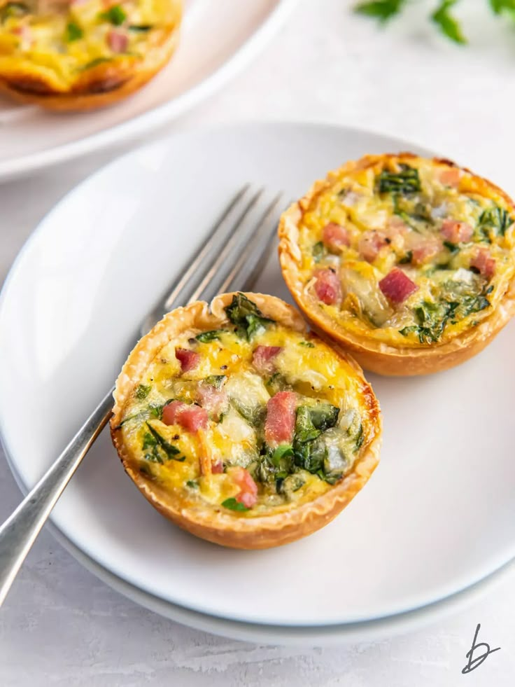 two small quiche pies on a white plate with a fork next to it