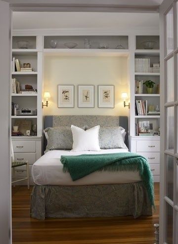 a bed sitting in the middle of a bedroom next to a book shelf filled with books