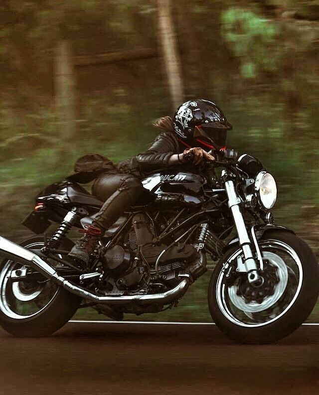 a person riding on the back of a motorcycle down a road with trees in the background