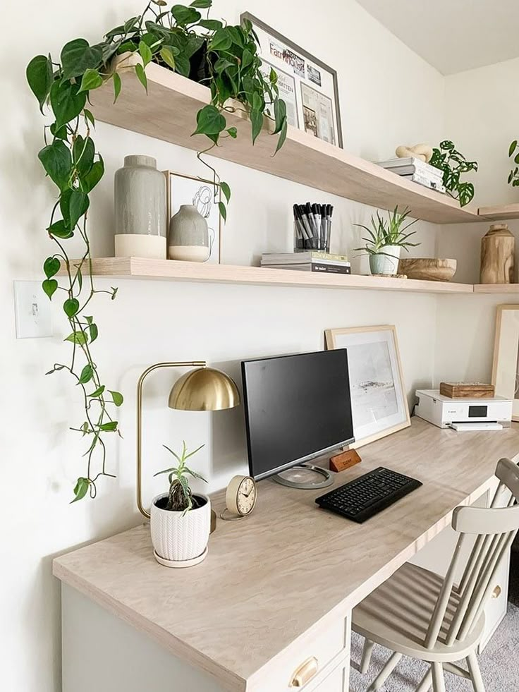 a desk with a computer on it and some plants in the corner next to it