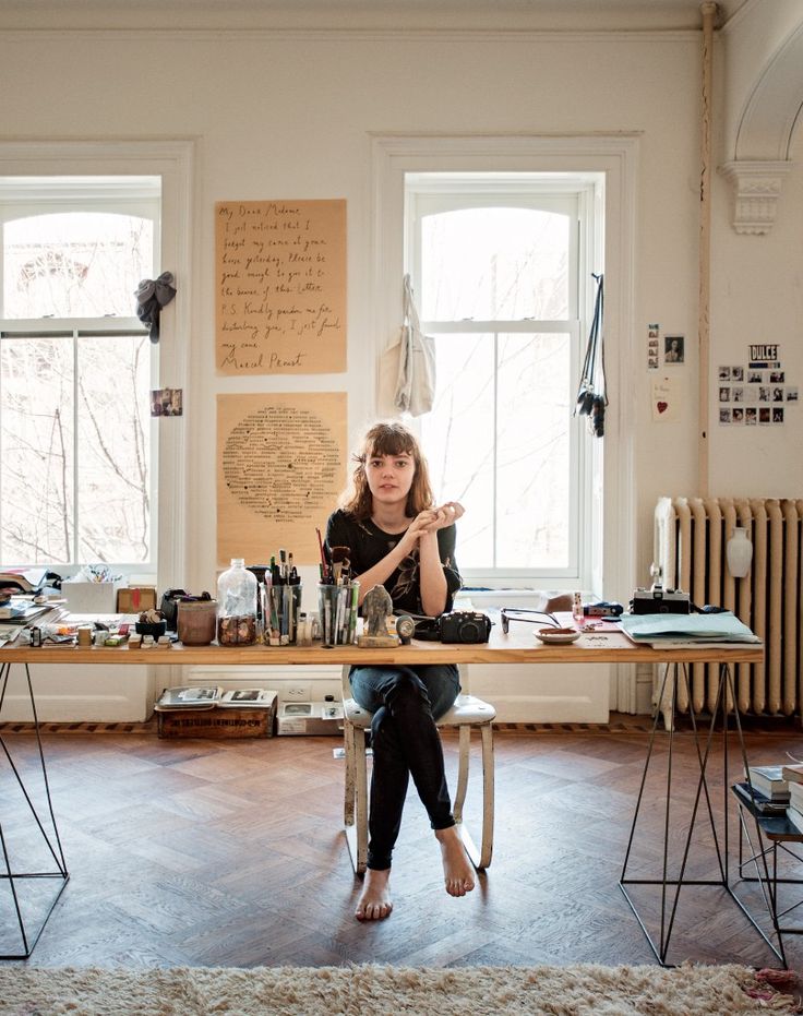 a woman sitting at a table in front of two windows