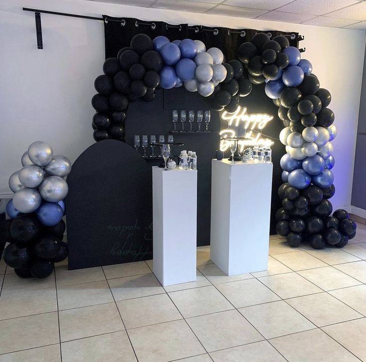 balloons and bottles are on display in front of a wall with black and silver decorations