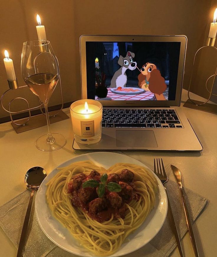 a white plate topped with spaghetti and meat next to a laptop computer on a table