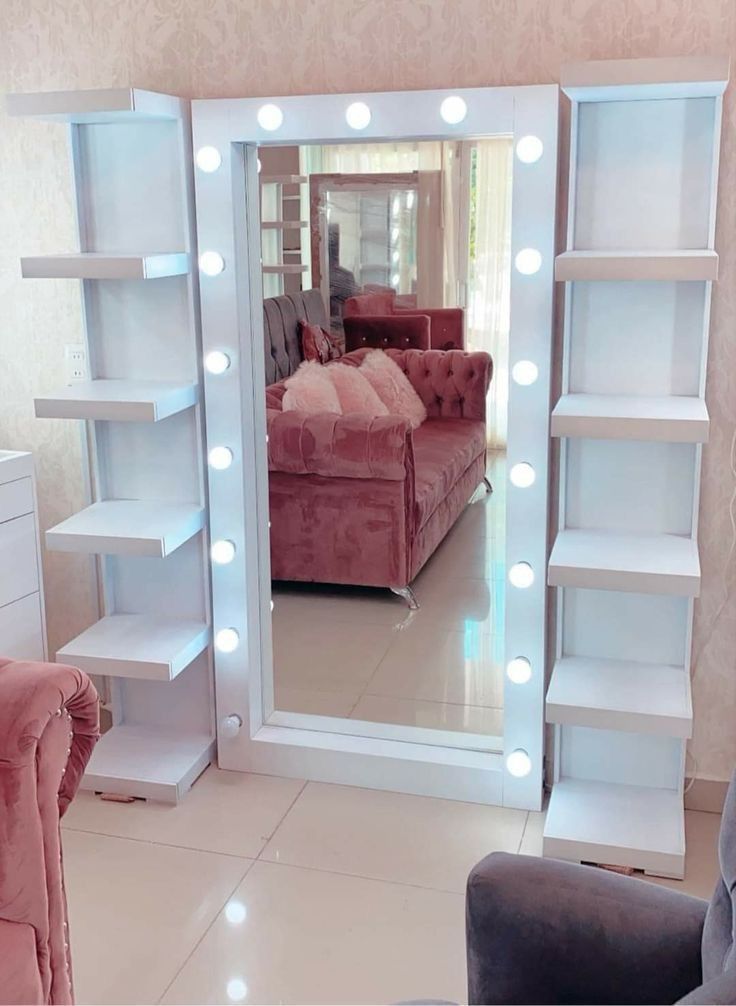 a mirror that has lights on it in the middle of a room with a couch