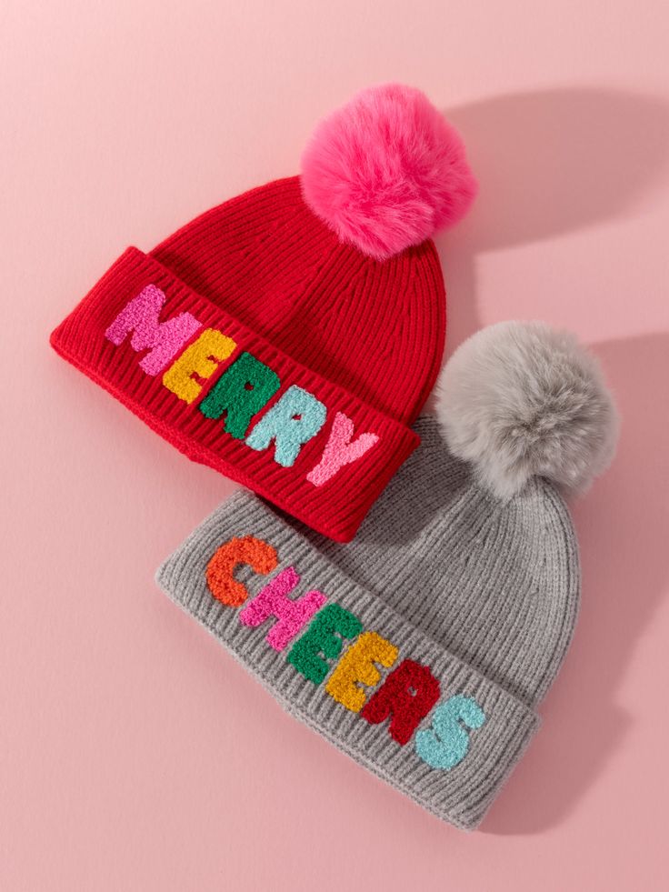 two knitted hats with pom - poms on top of each other and the word happy written in multicolored letters