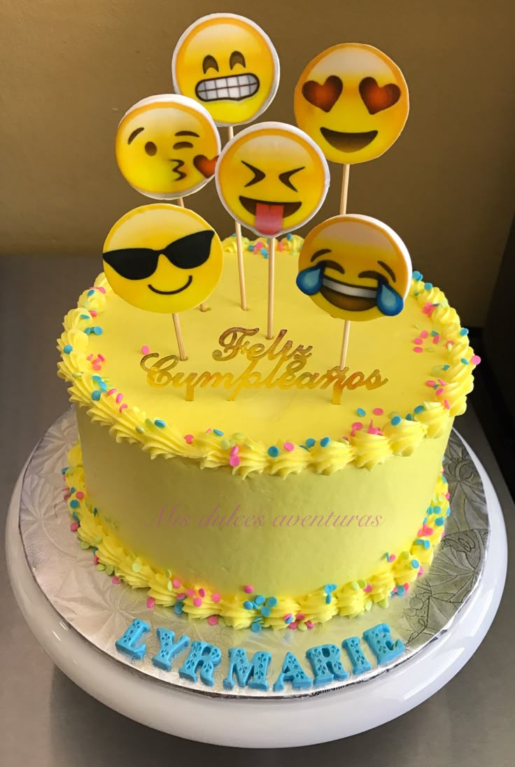 there is a yellow cake with smiley faces on it and some lollipops