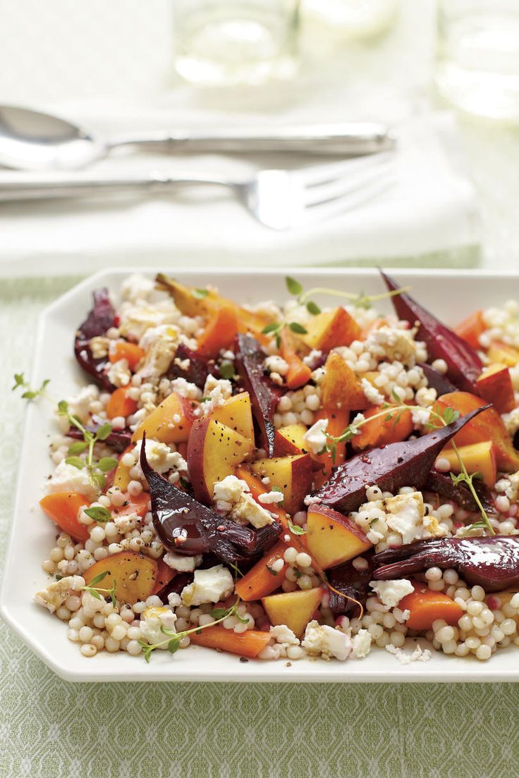 a white plate topped with carrots, corn and feta cheese next to silverware