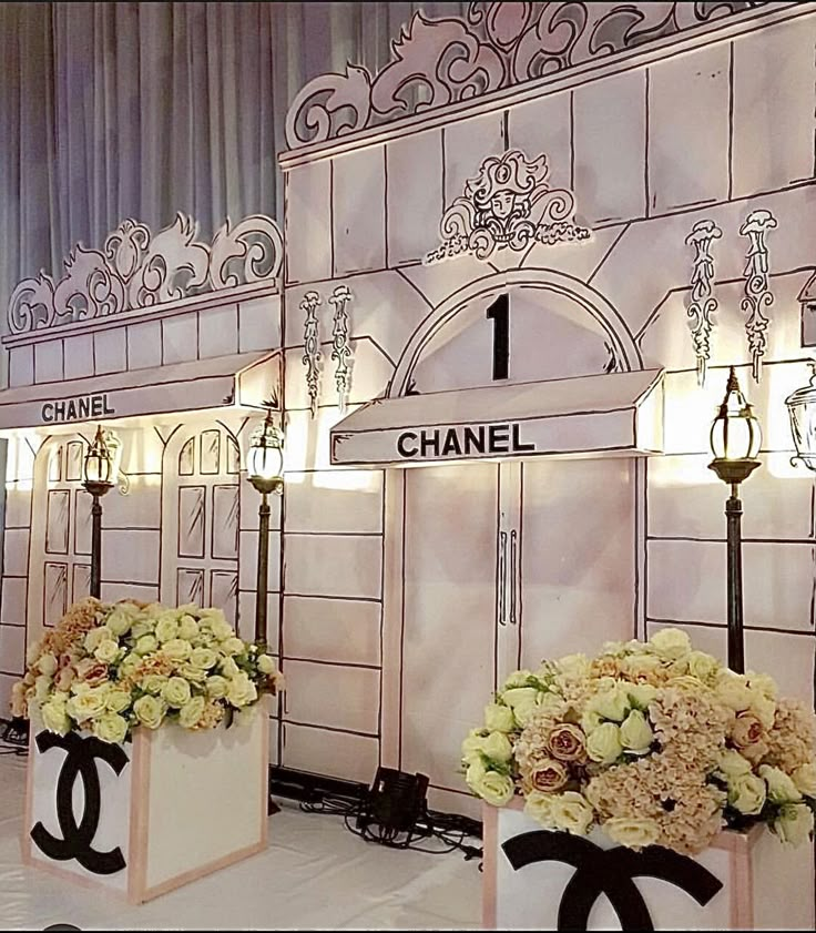 two chandeliers with flowers in front of them on display at a fashion show