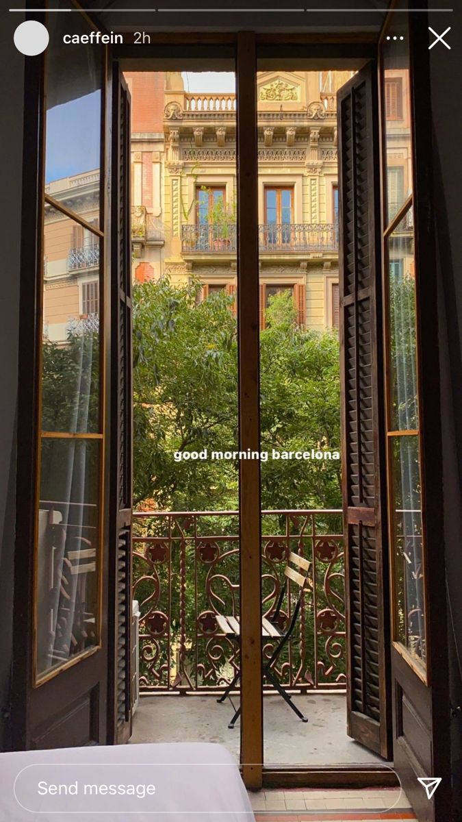 an open door leading to a balcony with a view of trees and buildings in the distance