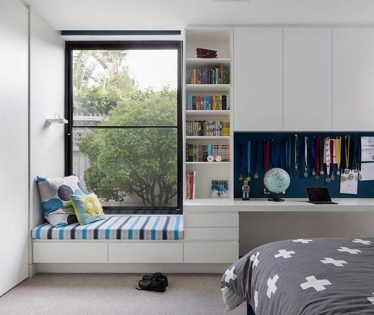 a bedroom with a window seat and bookshelf next to the bed in front of it