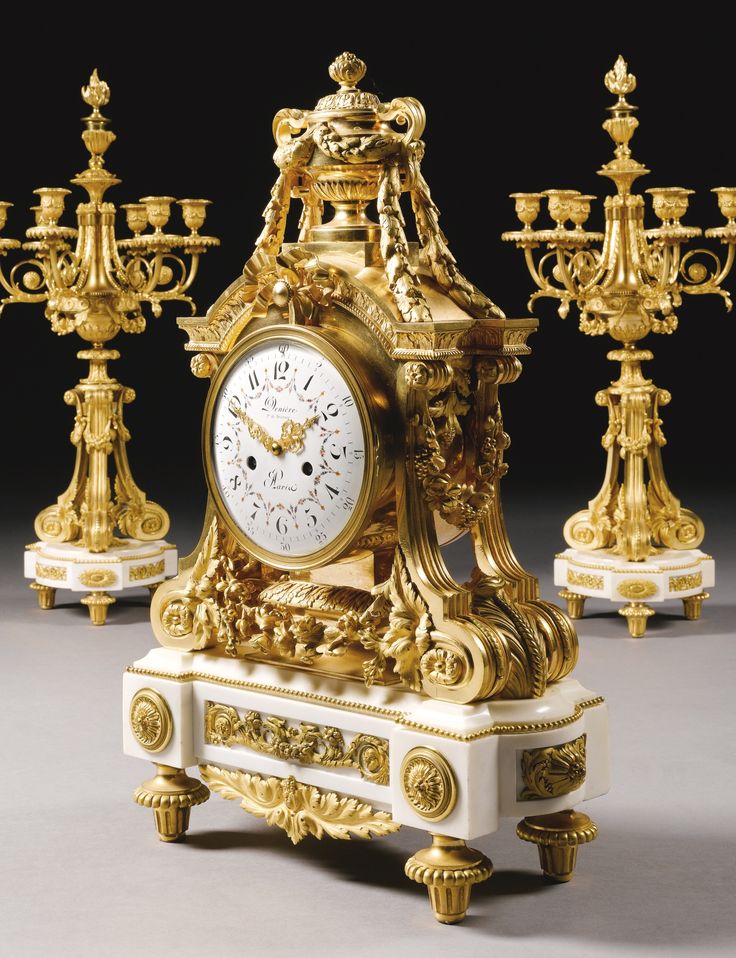 an ornate clock surrounded by golden candles and candelabras in the shape of chandeliers