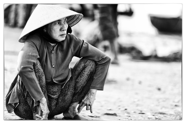 a woman in a hat crouches down on the ground with her hands behind her back