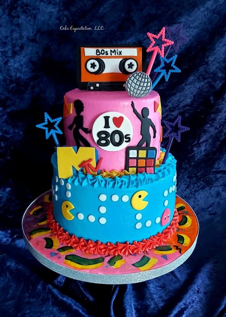 a birthday cake decorated with an 80's theme on a blue tablecloth background