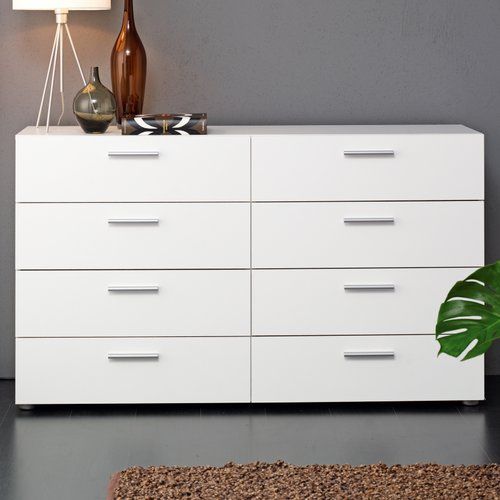 a white dresser sitting next to a lamp on top of a rug