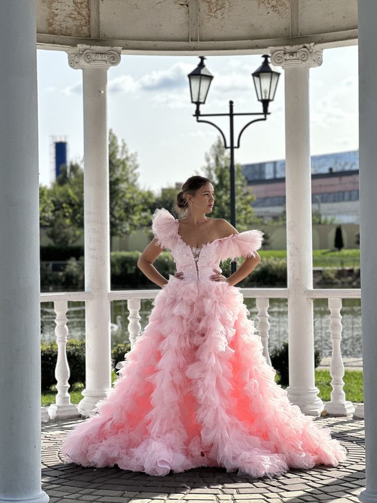 a woman in a pink dress standing on a porch