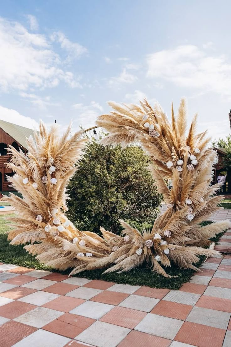 a wreath made out of dried grass and white flowers on a checkered floor in front of a building