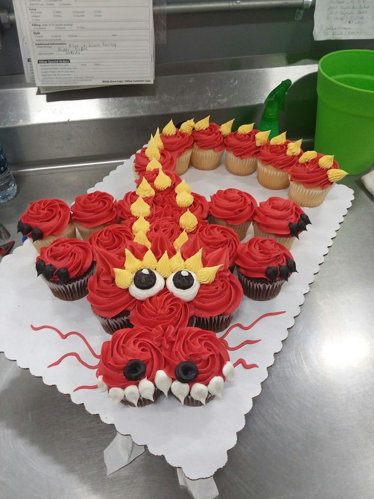 cupcakes decorated with red frosting and yellow icing are on a table