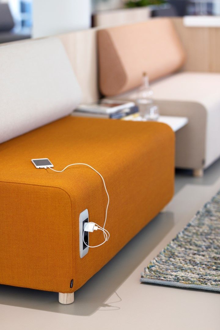 an orange couch sitting on top of a white floor next to a rug and table