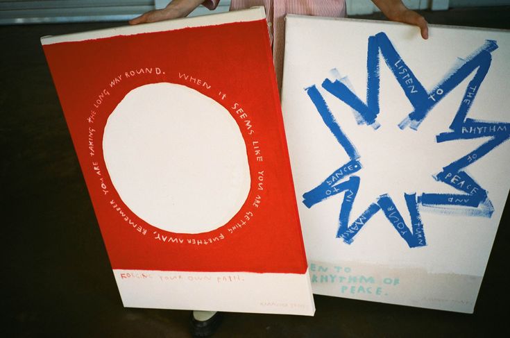 two people holding up posters with letters and numbers painted on them in blue, red, and white