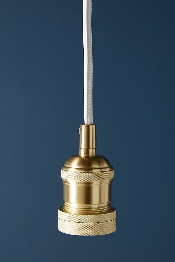 a brass colored light hanging from a white cord