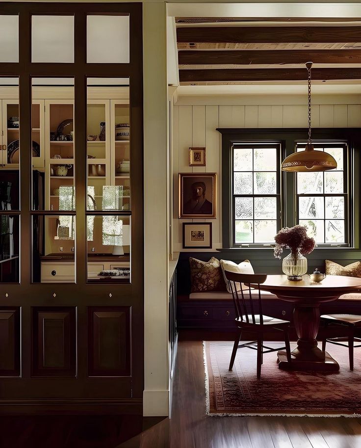 a dining room table and chairs in front of two windows with wooden beams on the ceiling