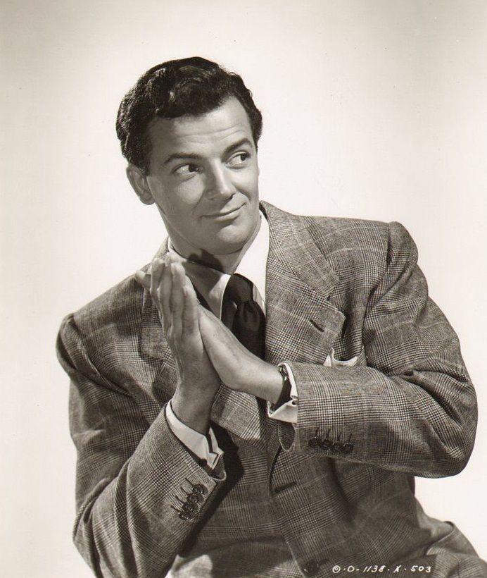 a black and white photo of a man in a suit with his hands folded up