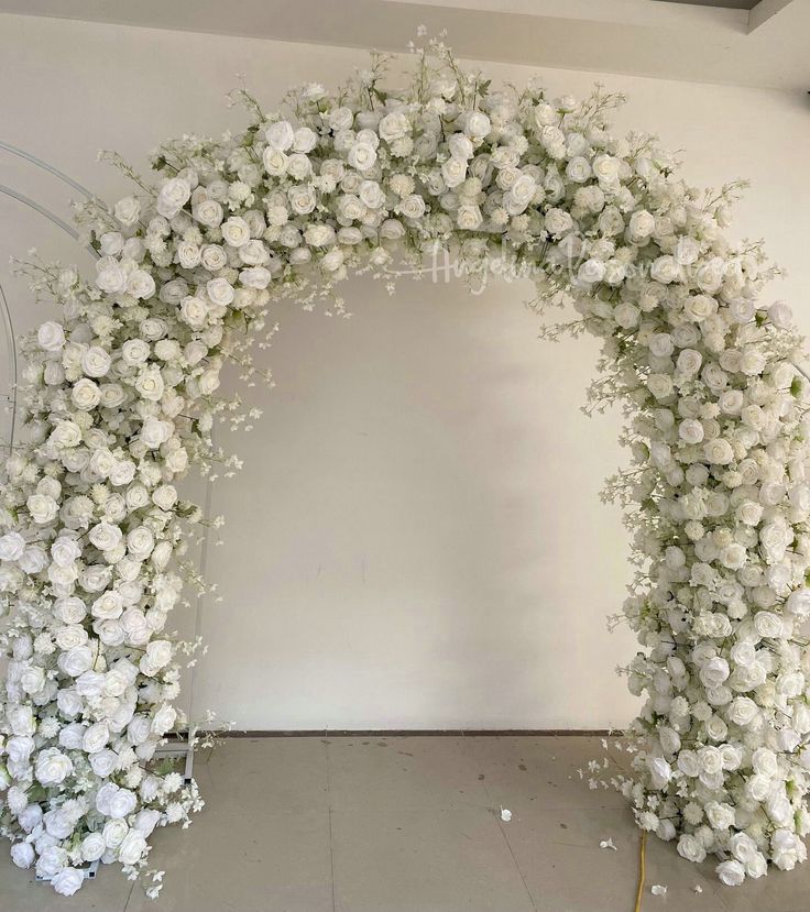 white flowers are arranged in an arch on the floor