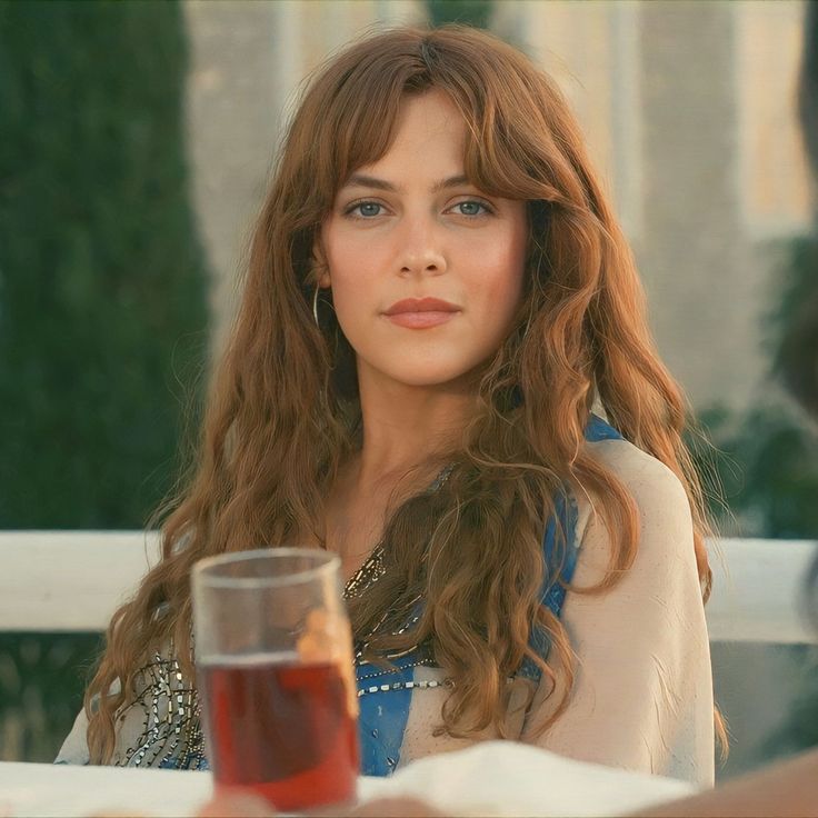 a woman sitting at a table with a glass of wine