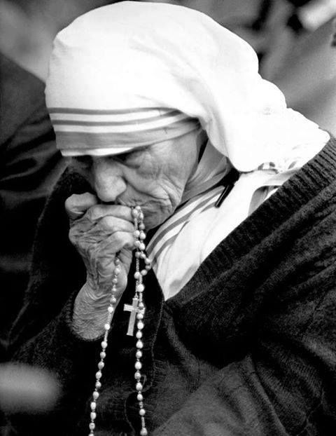 an old woman with a rosary on her hand and wearing a white headdress