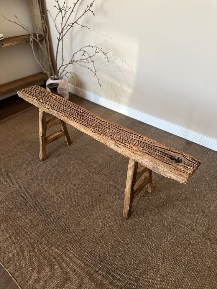 a wooden bench sitting on top of a carpeted floor next to a tree branch