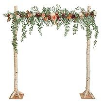 two tall trees with flowers and greenery on them are arranged in the shape of an arch