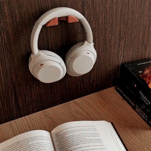 an open book sitting next to headphones on top of a wooden table with two books