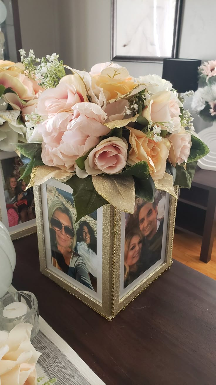 a vase filled with flowers sitting on top of a table next to two framed pictures