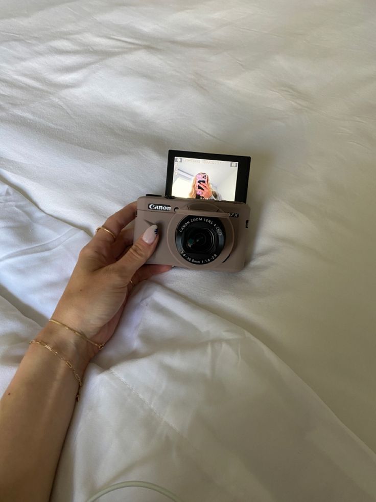 a person is holding a camera on top of a bed