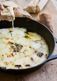 cheese being poured into a skillet with bread in the background