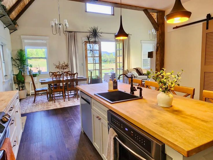 a kitchen with an island, stove and dining room table in the backround