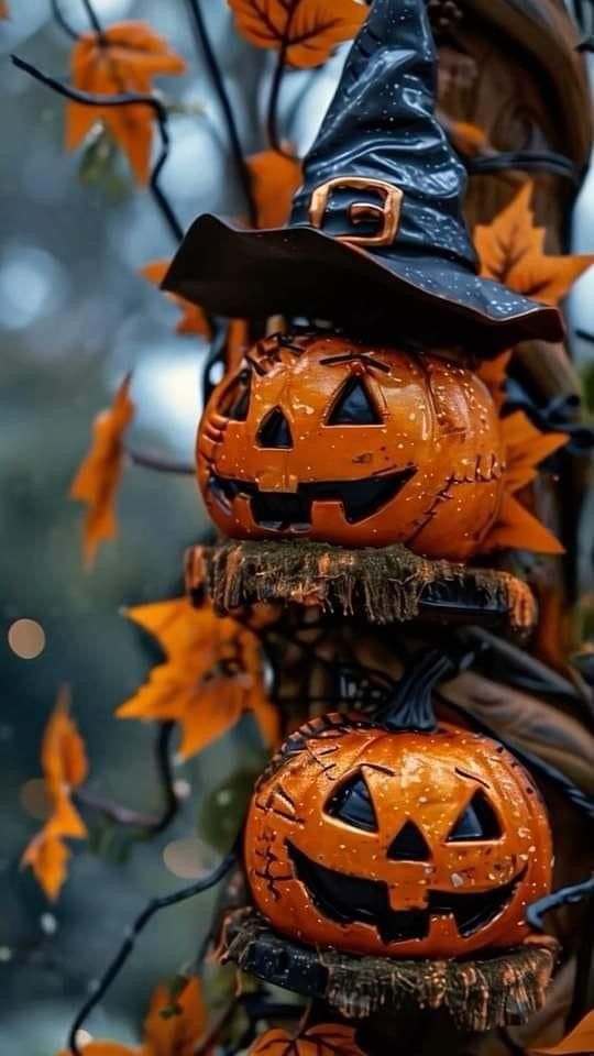 two pumpkins are stacked on top of each other in front of some trees with leaves