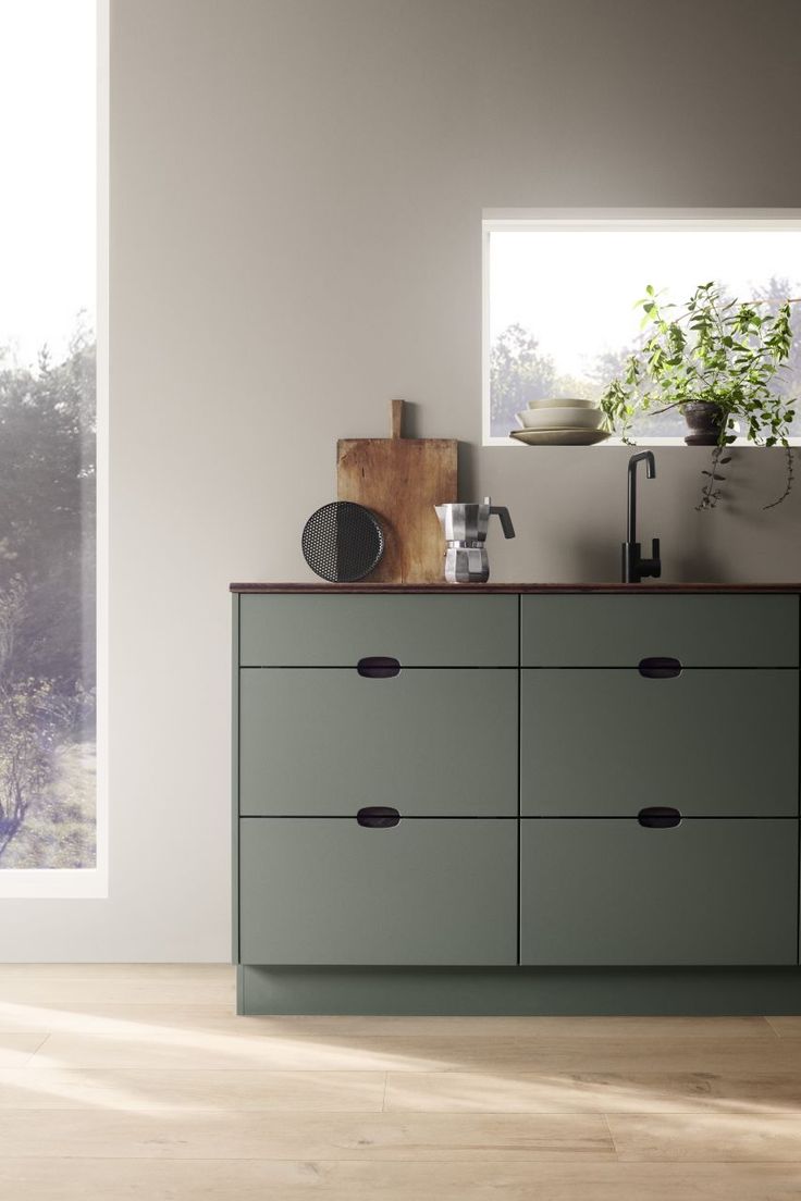 an empty room with a large green cabinet and wooden counter top, near a window