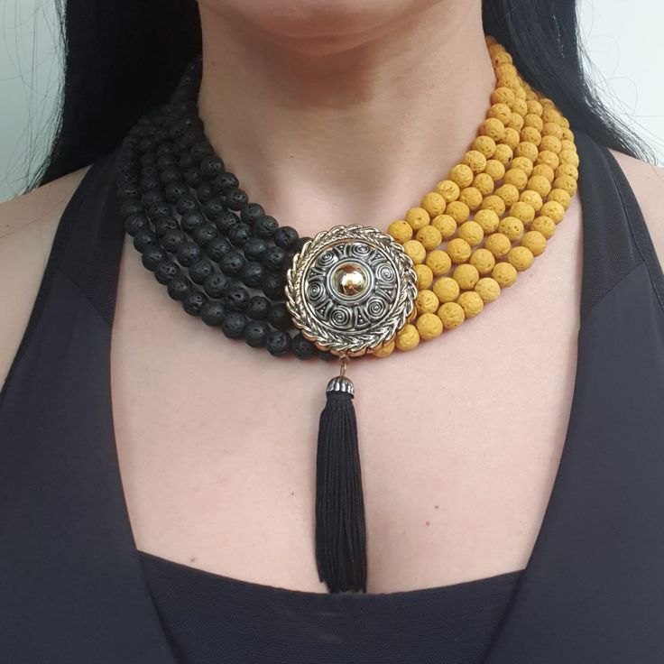 a woman wearing a yellow and black beaded necklace with tassels on it