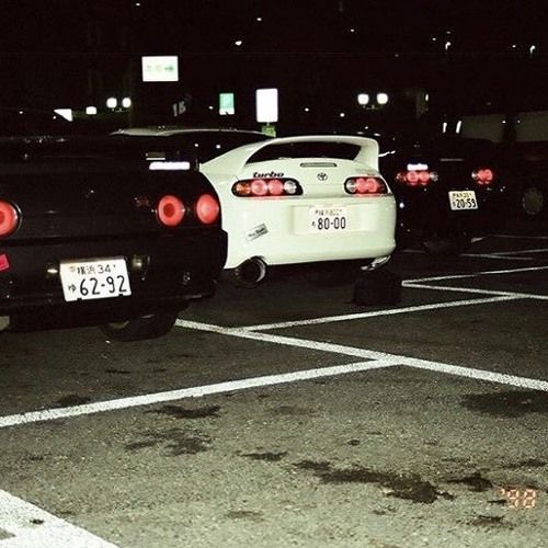 two cars parked in a parking lot at night with their lights turned on and the taillights showing